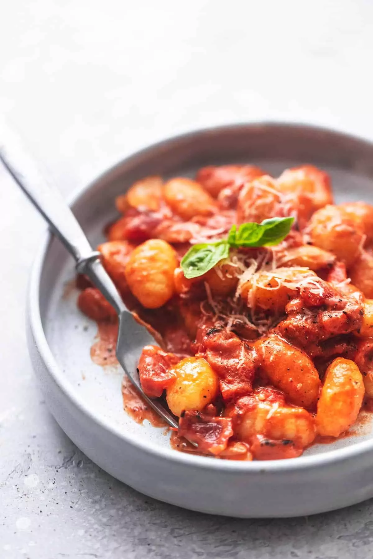Gnocchis dans une sauce à la crème de tomate avec une fourchette sur une assiette.