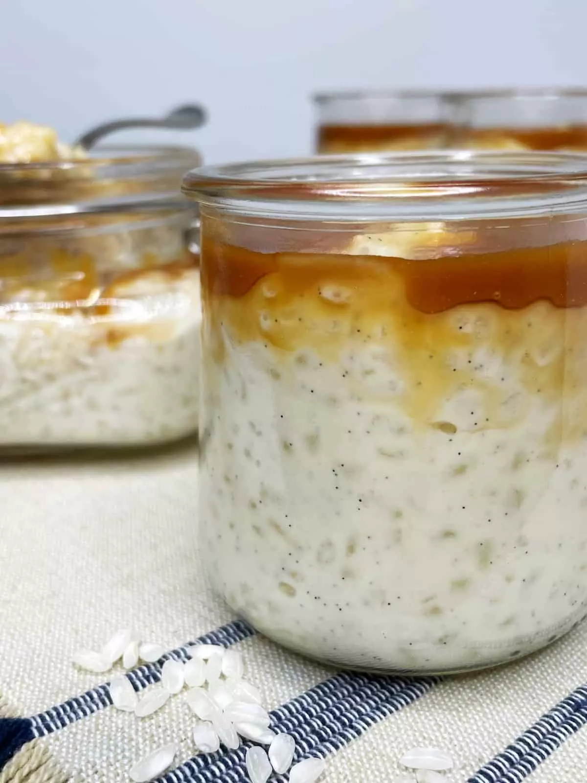 Two glass jars with rice pudding and rice grains in the background